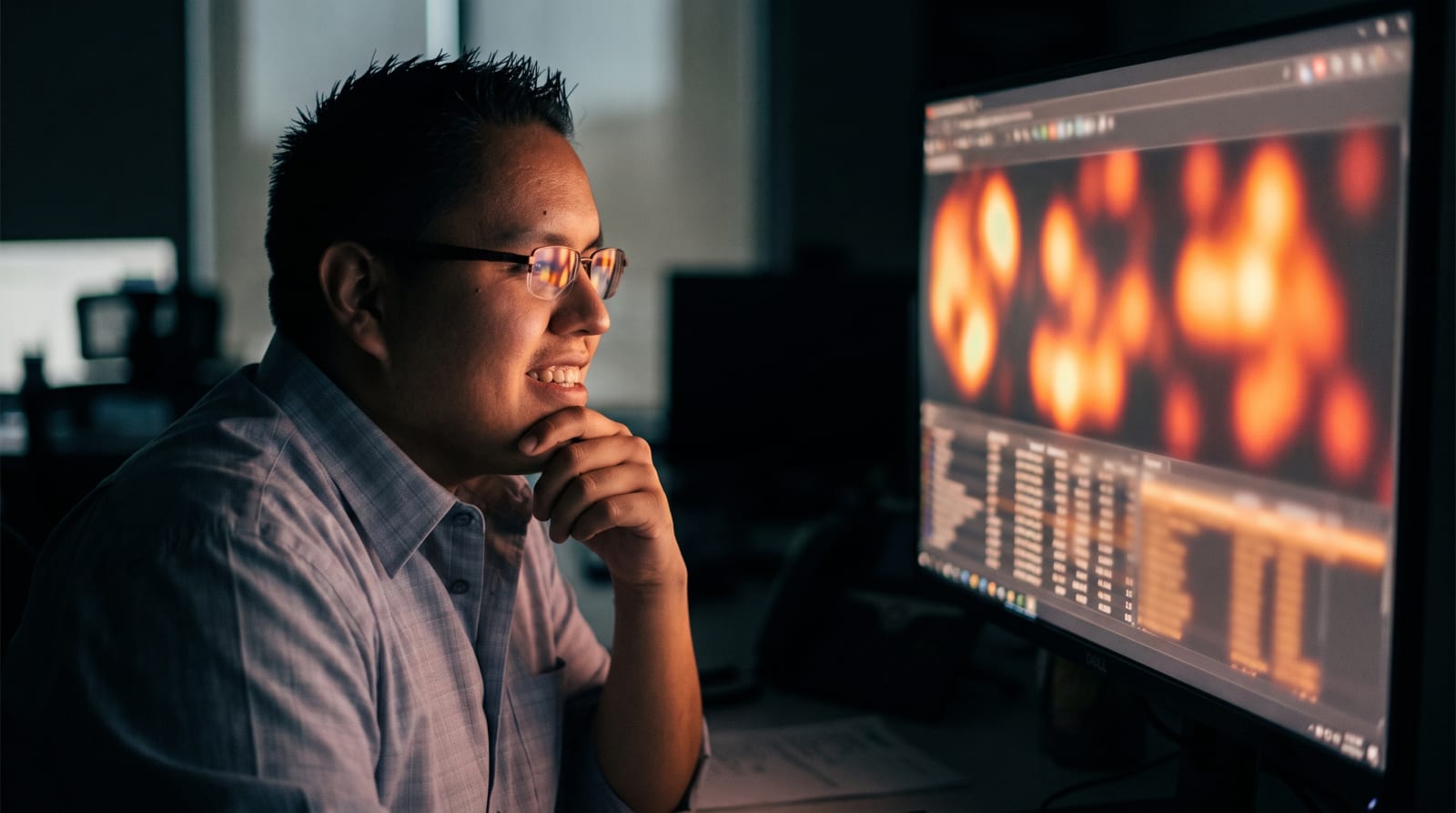 Savelle McThias studying heat-map data on a large monitor in a dim office